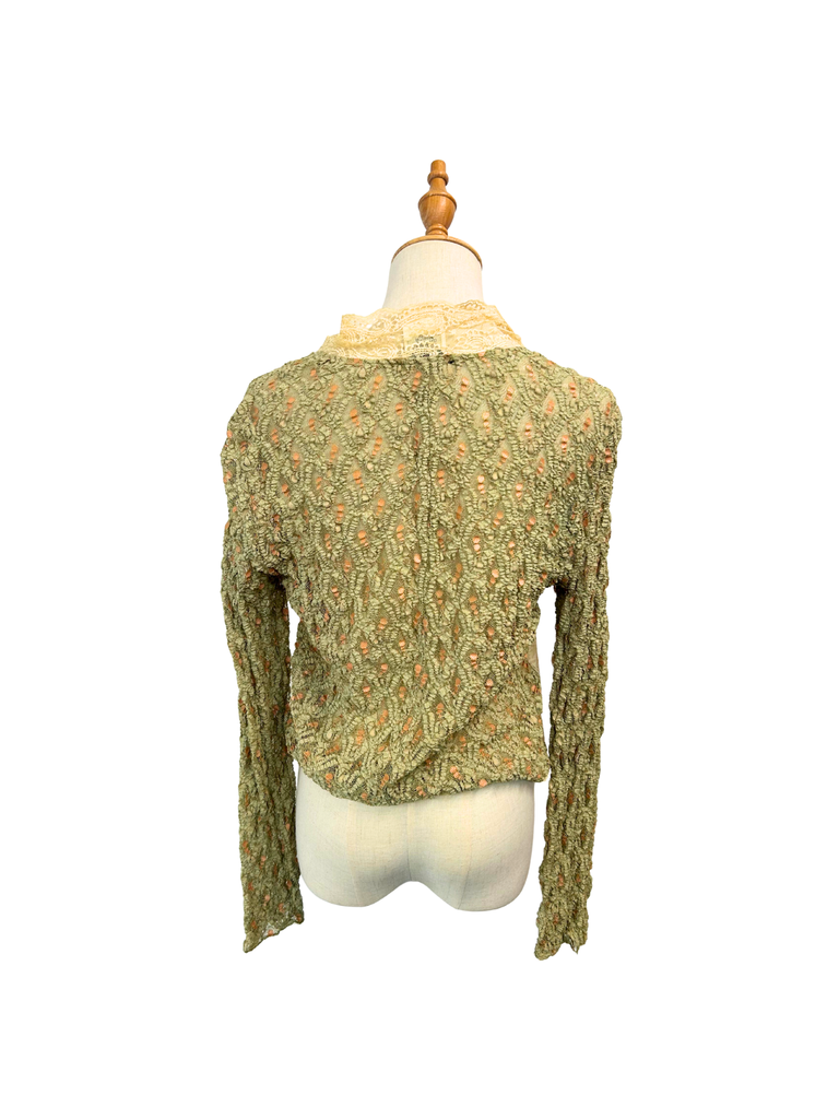 The back view of a long sleeve printed lace women's shirt that is in green, blue and neutral shades and has a zipper