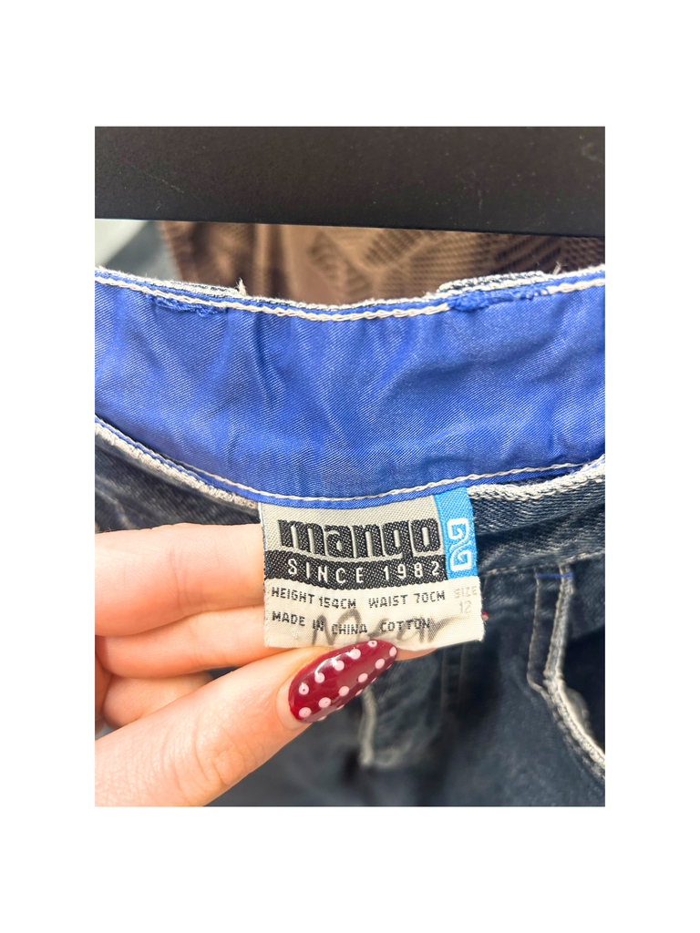 Closeup view of brand label from a pair of vintage blue denim Mango Jorts with red, white and blue stripes on each side 